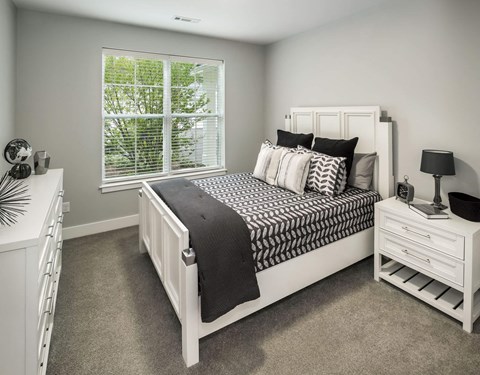 A bedroom with a large bed and a window with blinds.