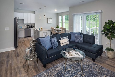 A modern living room with a black sofa and a glass coffee table.