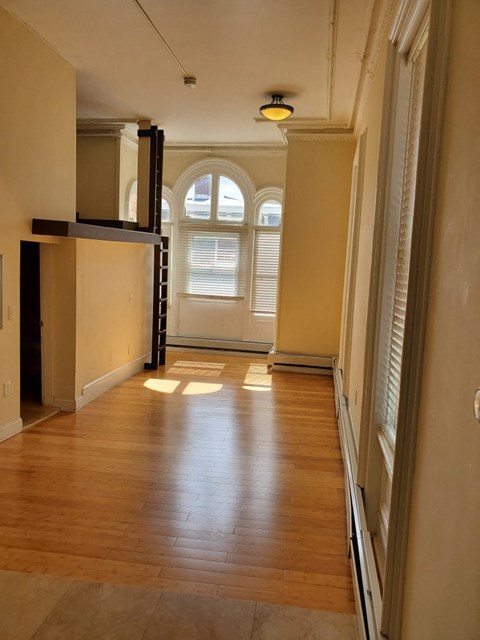 an empty living room with wooden floors and a window