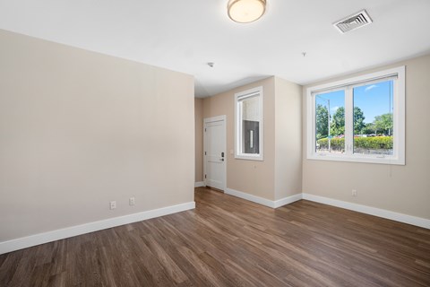 an empty living room with wood flooring and a window