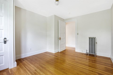 a living room with white walls and wood floors and a radiator