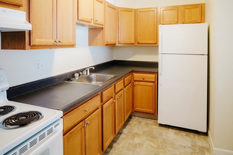 a kitchen with wooden cabinets and a white stove and refrigerator