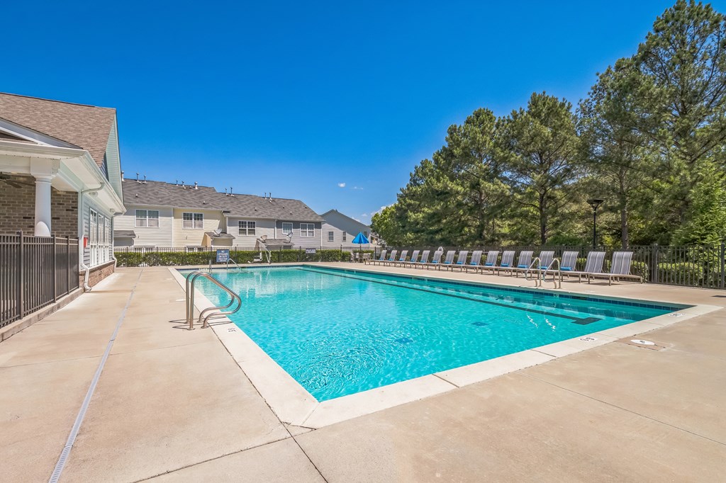 A large outdoor swimming pool surrounded by a concrete patio and lounge chairs at The Atlantic Mountain Island, Charlotte