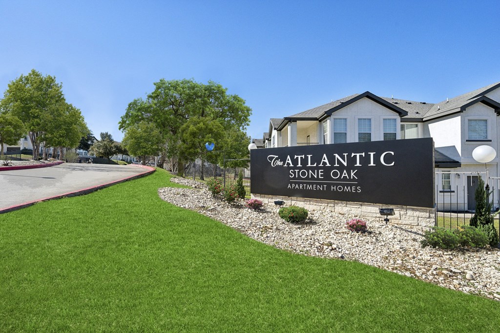 A sign for Atlantic Stone Oak Apartment Homes is in front of a building.