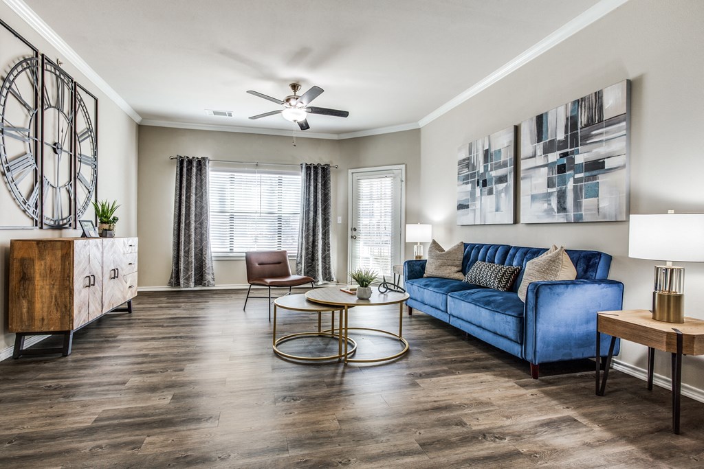 a living room with a blue couch and a coffee table at Village of Hawks Creek Apartments, Texas