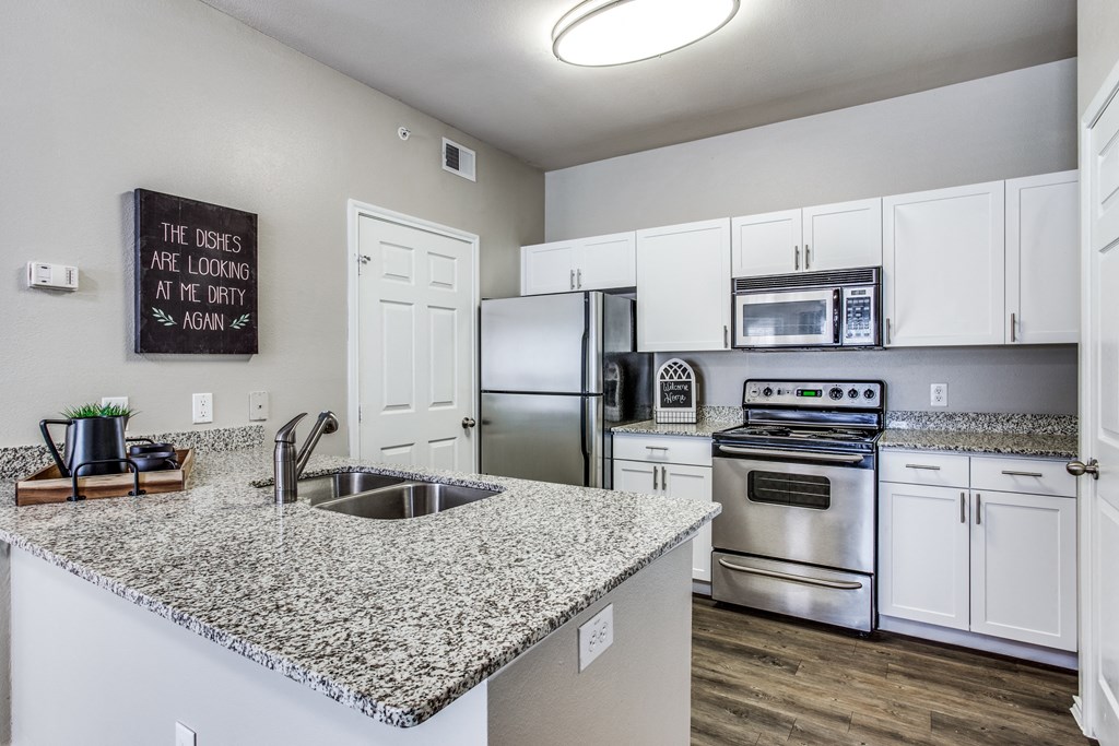 a kitchen with granite counter tops and stainless steel appliances at Village of Hawks Creek Apartments, Westworth Village, TX 76114