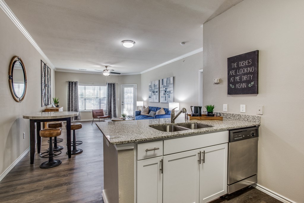 an open kitchen and living room with a counter top and a sink at Village of Hawks Creek Apartments, Texas