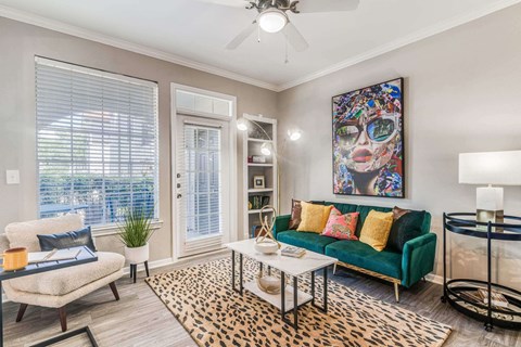 a living room with a green couch and a ceiling fan