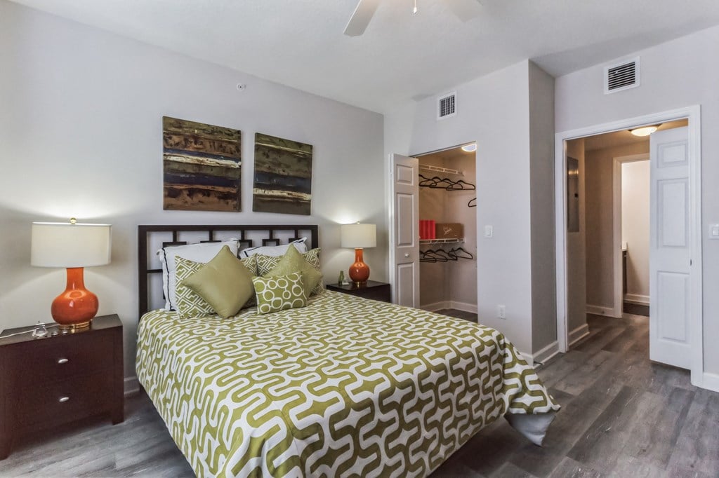 a bedroom with a bed and two night stands and a door to a bathroom