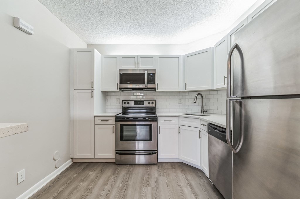 an empty kitchen with stainless steel appliances and white cabinets. Select units.