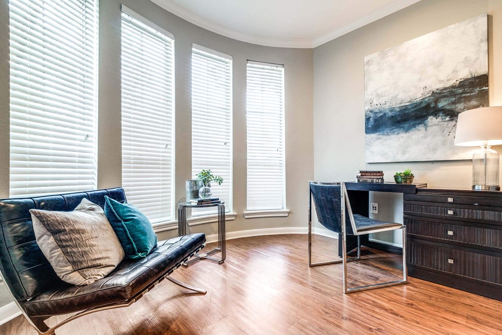 Living room with a leather couch and a desk and three windows at Vintage Park Apartments, Houston, TX