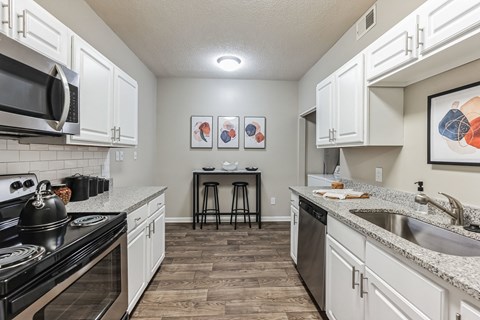 a spacious kitchen with white cabinets and granite counter tops