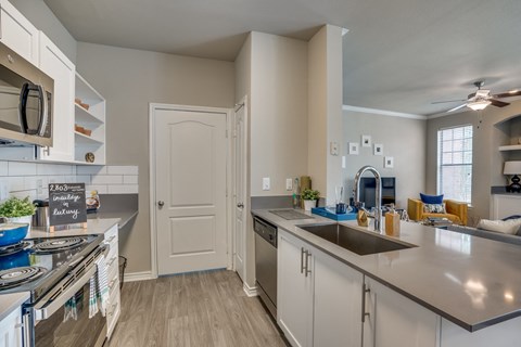 an open kitchen with stainless steel counters and appliances and a door to the living room