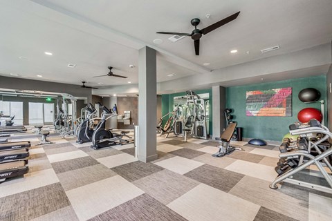 Gym with weights and cardio machines and a ceiling fan at The Atlantic Highland Park, Dallas, Texas