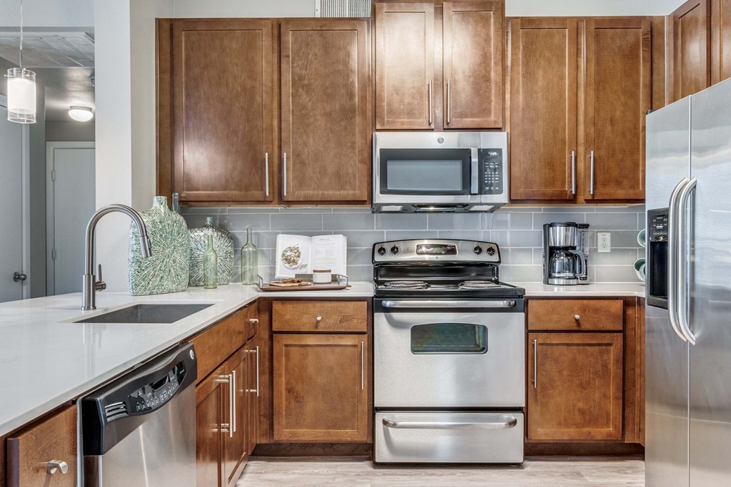 Kitchen with stainless steel appliances and wooden cabinets at The Atlantic Highland Park, Dallas