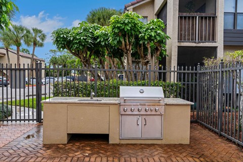 A small outdoor kitchen with a grill and sink at Boca Colony Apartments, Boca Raton, Florida