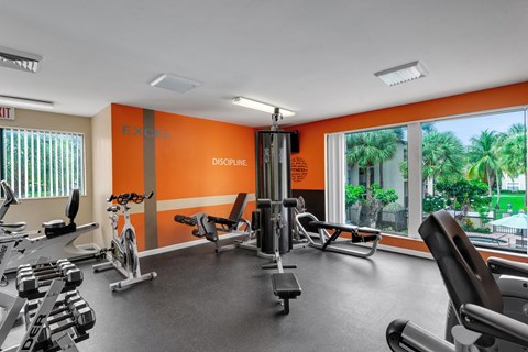 A gym with orange walls and a variety of equipment. A gym with orange walls and a variety of equipment at Boca Colony Apartments, Boca Raton