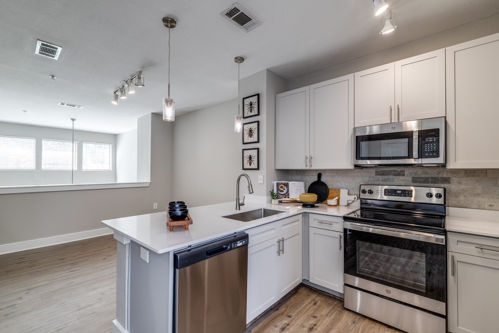 A modern kitchen with white cabinets and stainless steel appliances at The Atlantic Memorial, Houston