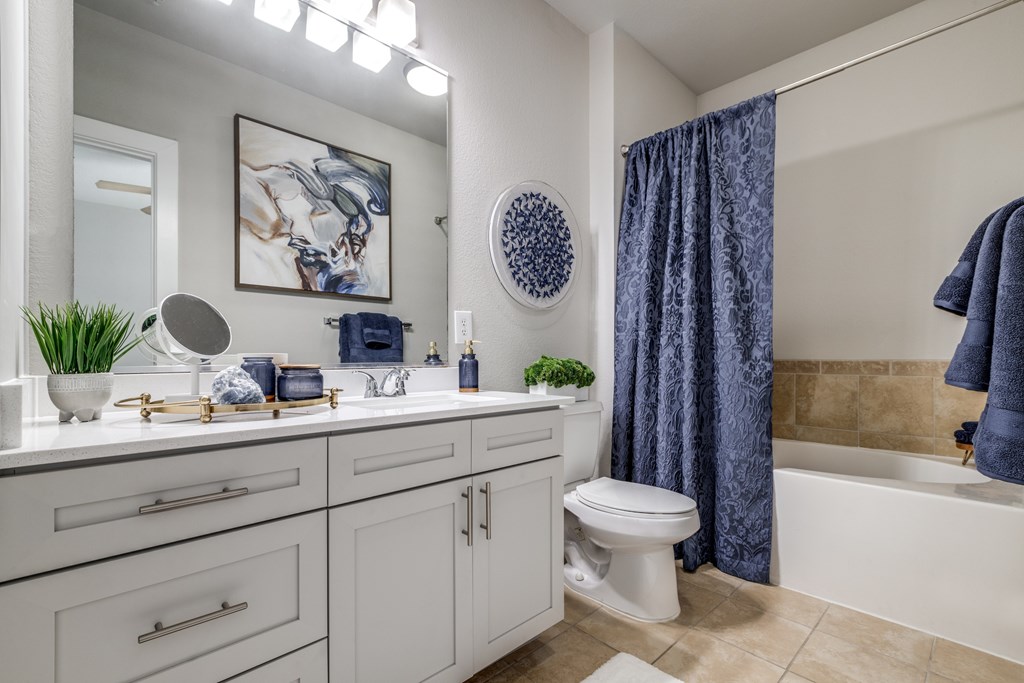 A bathroom with a white toilet and a blue shower curtain at The Atlantic Memorial, Houston