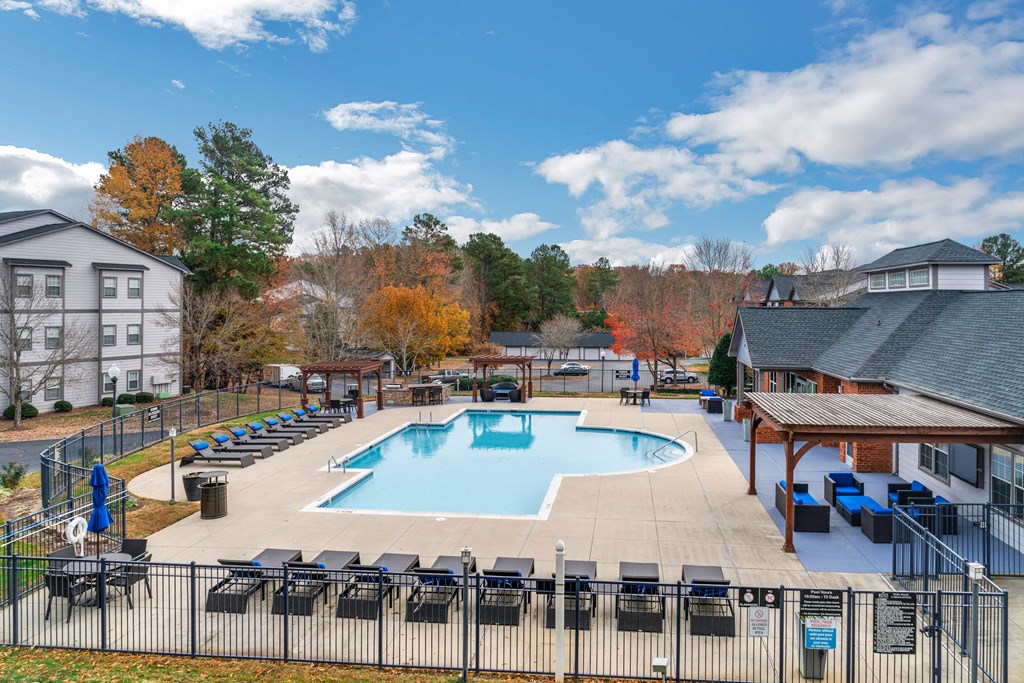 our resort style swimming pool is surrounded by chairs and a building