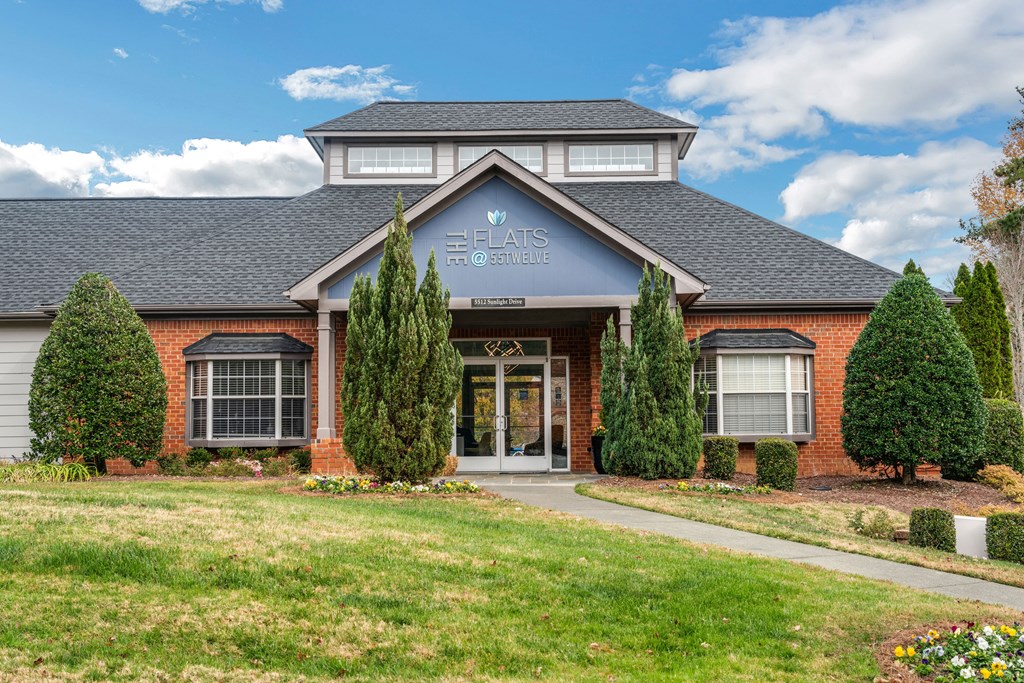 the front of a house with a lawn and trees in front of it
