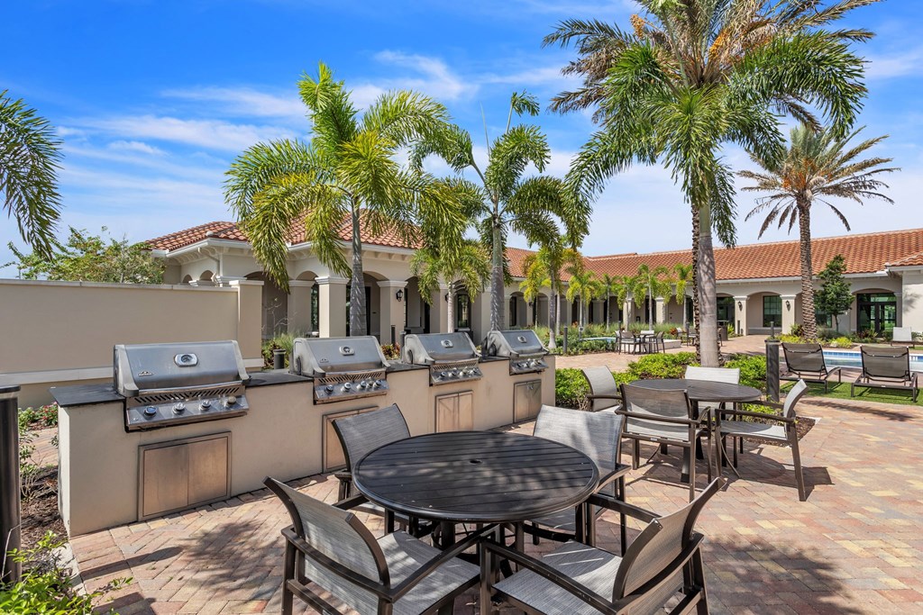 a patio with a table and chairs and barbecue grills