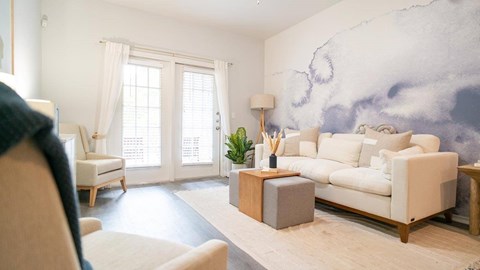 A living room with a white sofa, a wooden side table, and a large painting on the wall.