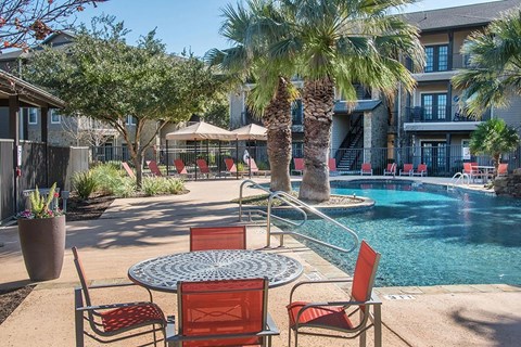 Resort style pool deck with lounge seating at The Palmera Apartments, Texas
