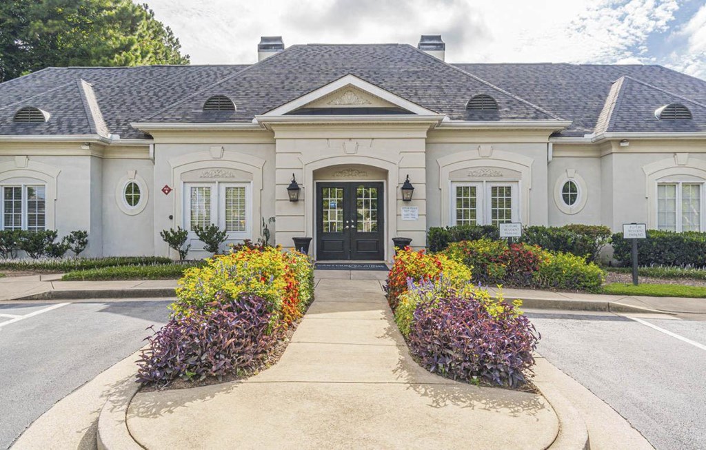 A white building with a black door and windows surrounded by flowers.at The Atlantic Canton Ridge, Canton