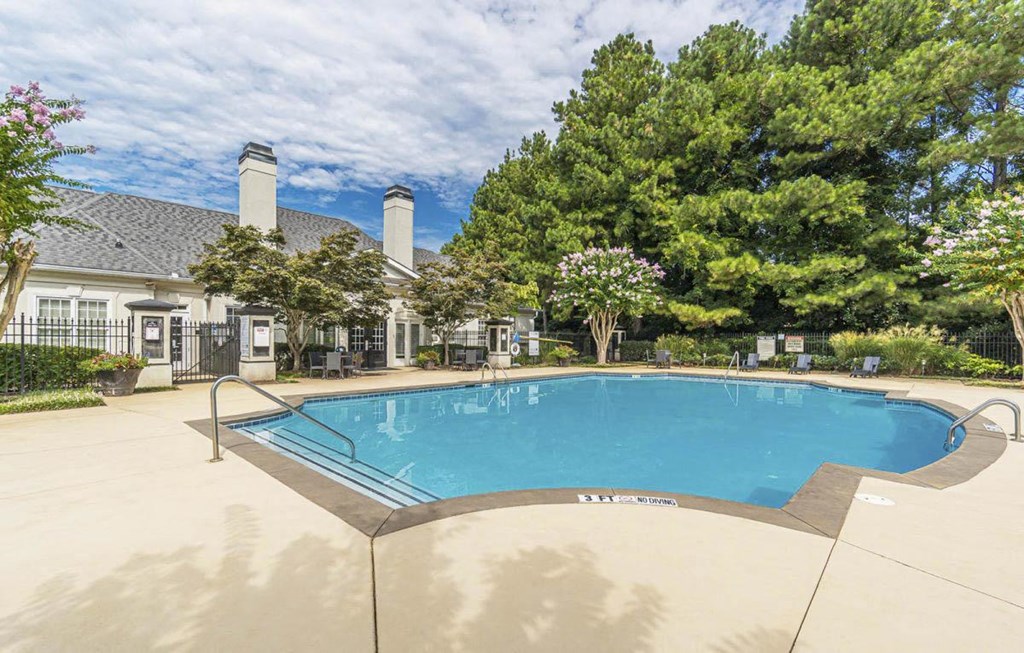 A large outdoor swimming pool surrounded by a fence and trees.at The Atlantic Canton Ridge, Georgia