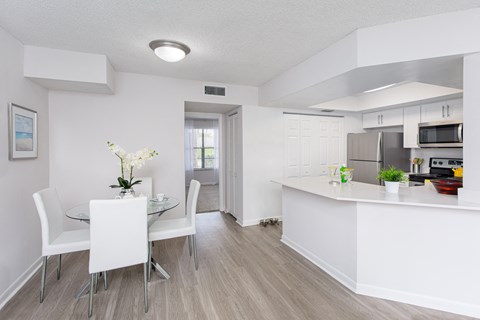a dining room with a table and chairs and a kitchen with a sink