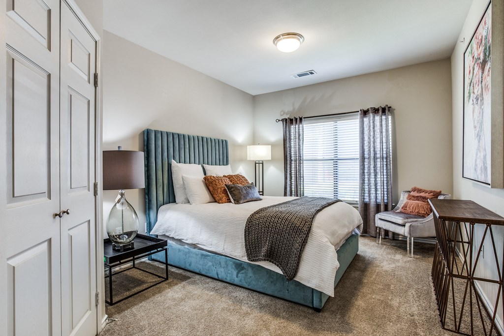 a bedroom with a bed and a chair and a window at Village of Hawks Creek Apartments, Westworth Village, TX 76114