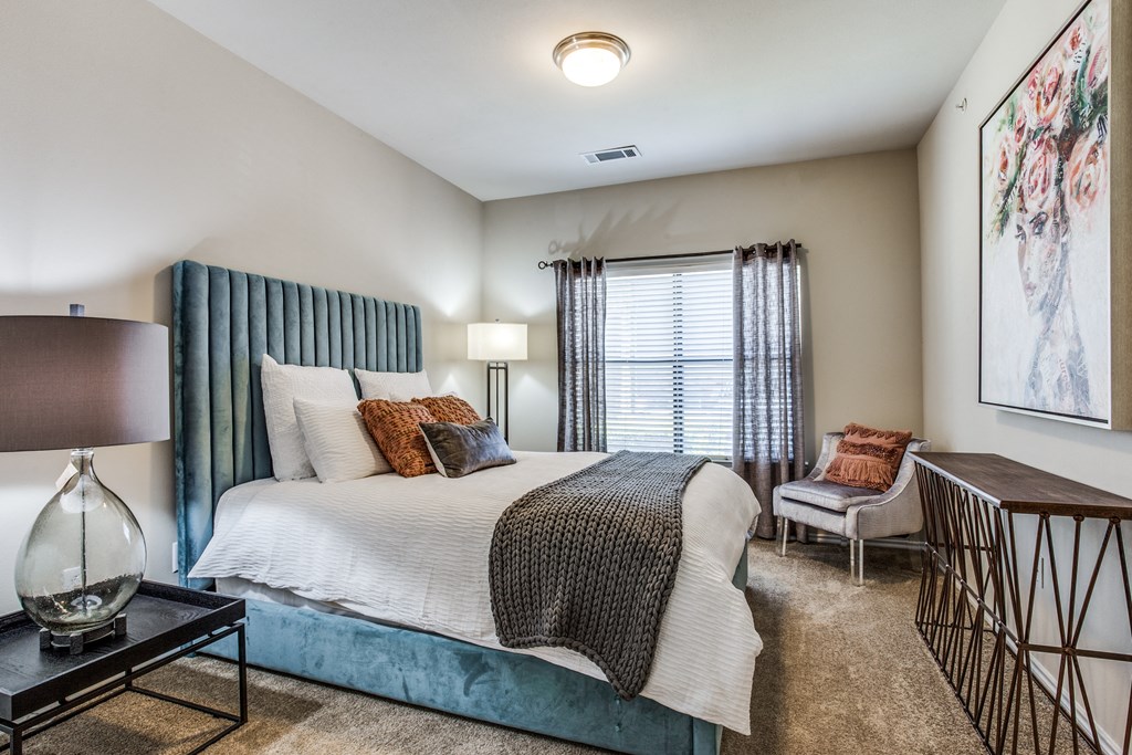 a bedroom with a bed and a chair and a window at Village of Hawks Creek Apartments, Westworth Village