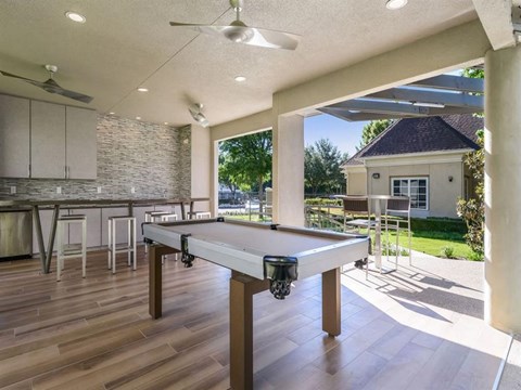 a pool table in an outdoor entertaining area with a kitchen