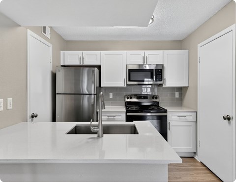 A kitchen with white cabinets and appliances.