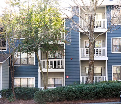 the exterior of a blue apartment building with trees and shrubs at The Atlantic Vinings, Georgia, 30080
