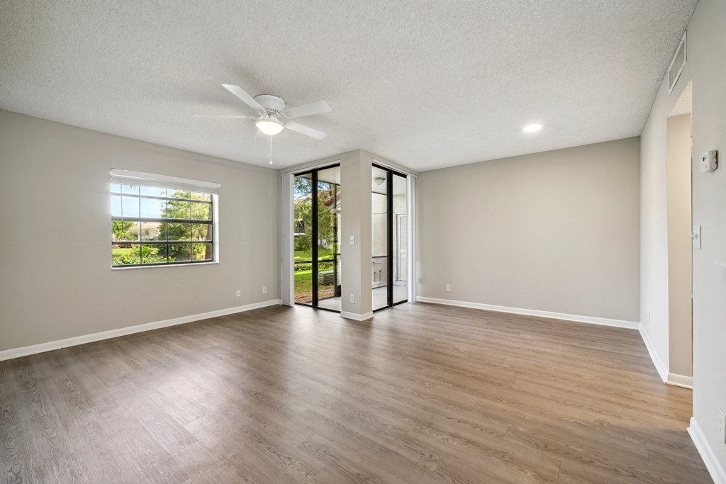 an empty living room with a ceiling fan and a window. Select units.