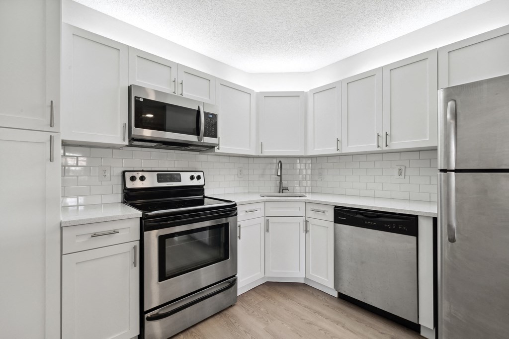 an empty kitchen with stainless steel appliances and white cabinets. Select units.