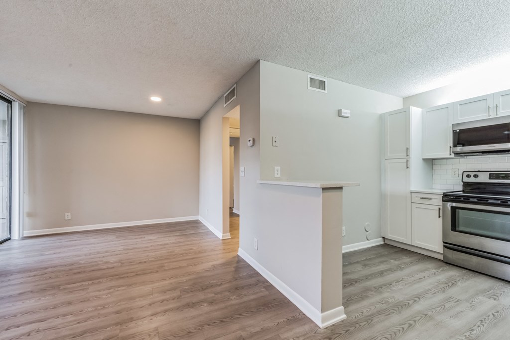 the living room and kitchen of an apartment with stainless steel appliances. Select units.