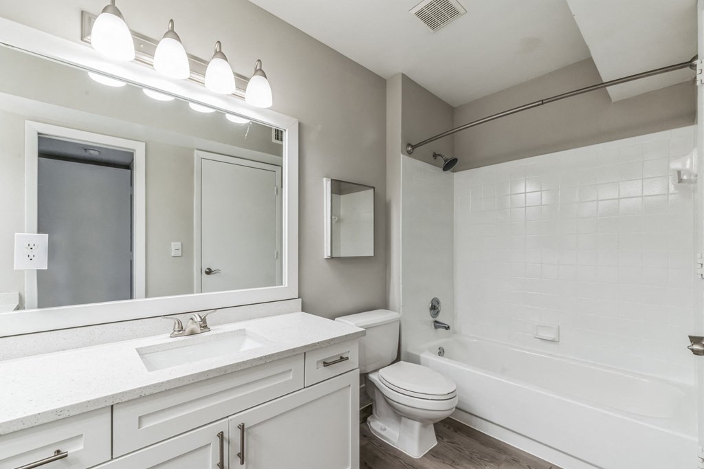 a white bathroom with a large mirror and a white toilet. Select units.