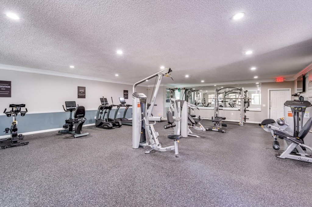 A spacious gym with a variety of equipment including treadmills, weights, and exercise machines. at Montecito Apartments, Houston