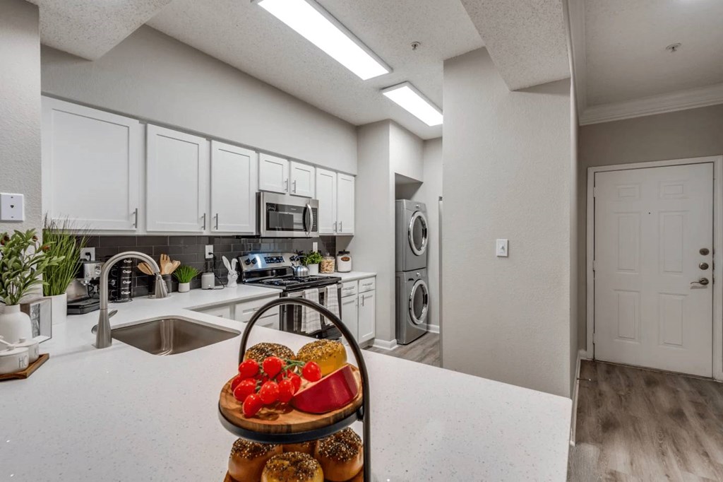 A kitchen with a white countertop and a basket of bagels and tomatoes on it. at Montecito Apartments, Houston, TX, 77056