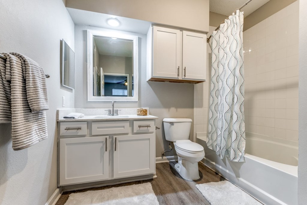 A bathroom with a toilet, sink, and a shower curtain. at Montecito Apartments, Texas