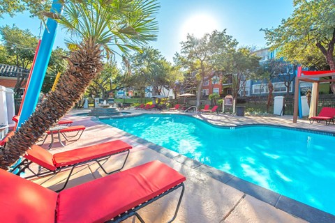 A pool with red chairs and a palm tree at Reserve at Canyon Creek,San Antonio, Texas