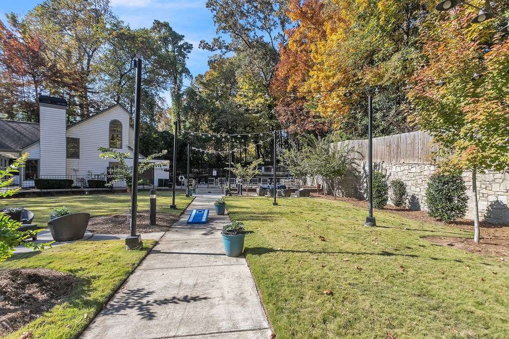 Backyard with a sidewalk and a yard with trees and a fence at The Atlantic Briarcliff, Atlanta, Georgia