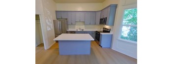 an empty kitchen with a white counter top