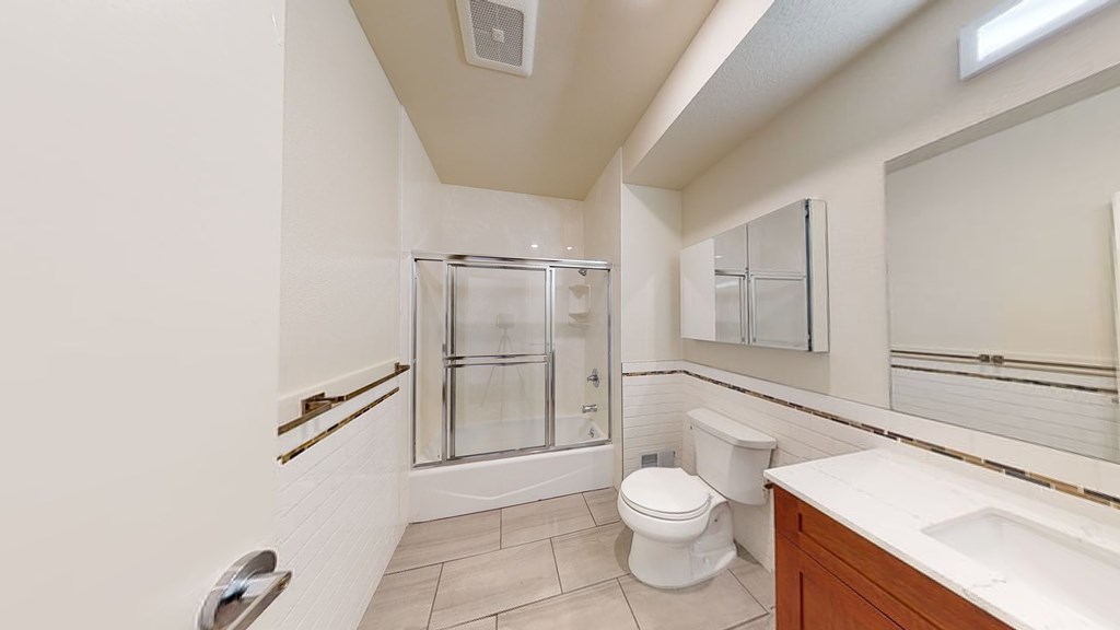 A white toilet sits in a bathroom with a walk-in shower.