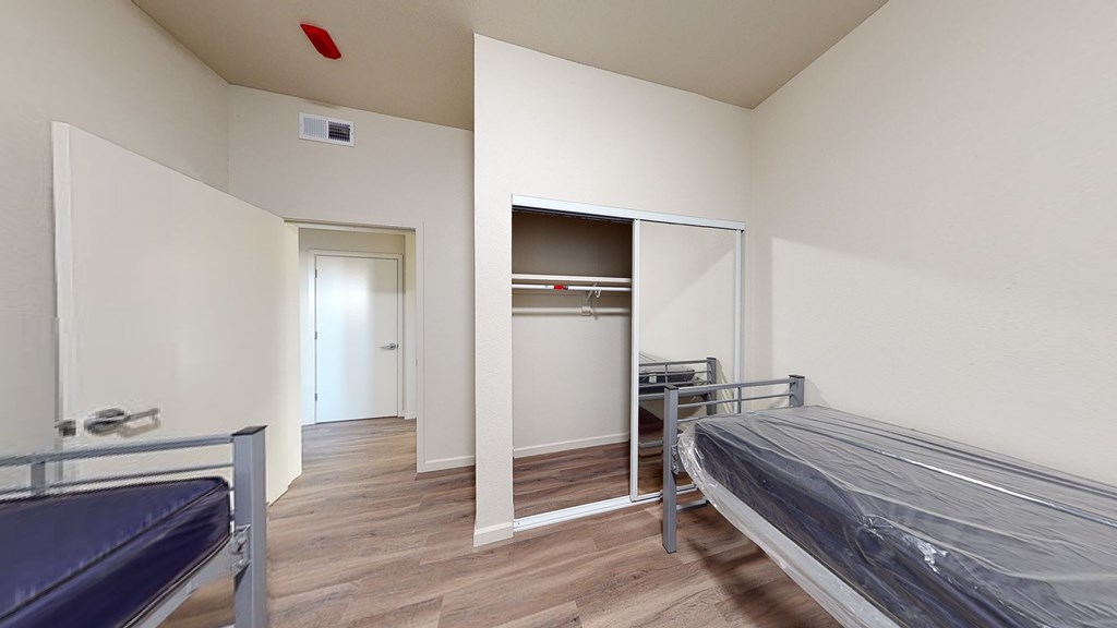 A room with a bed, a bench, and a closet.