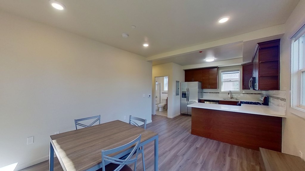 A kitchen with a table and chairs in the foreground and a refrigerator in the background.