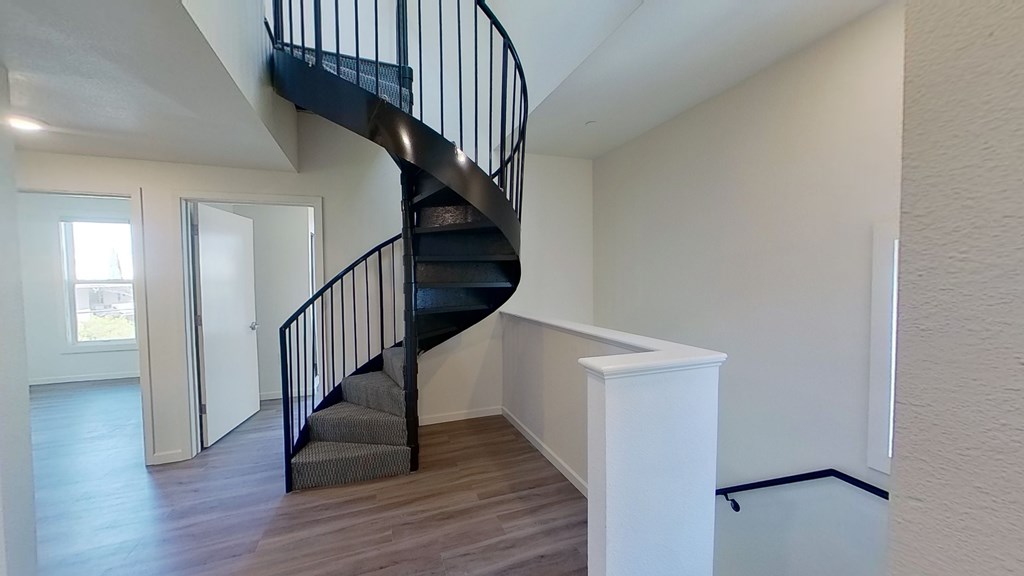 A spiral staircase in a room with wooden floors and white walls.